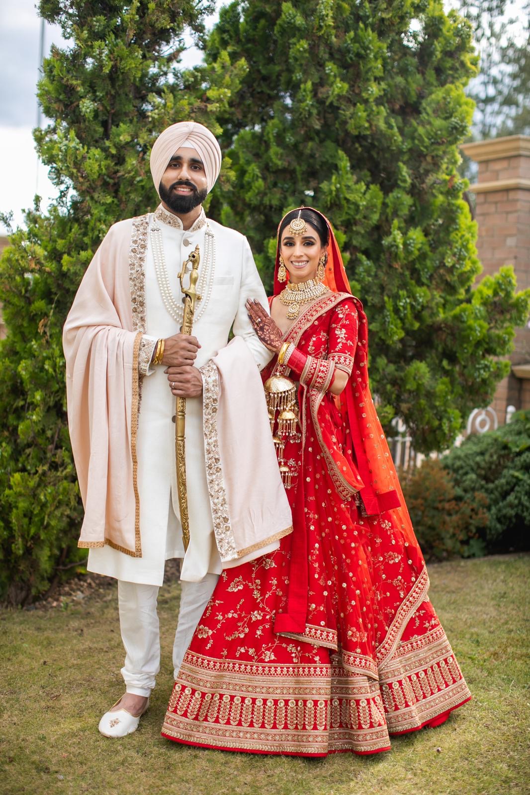 Kiran and Bal, founders of Virsa Matchmaking, photographed on their own wedding day — Bal in an ivory sherwani and turban holding a kirpan, Kiran in a red bridal lehenga with chooda and kalire